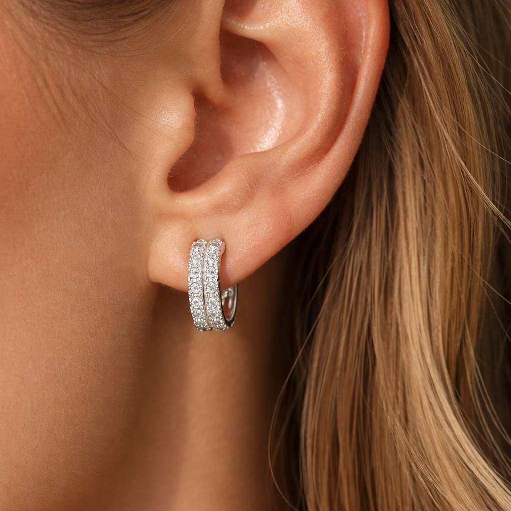 Close-up of an ear wearing a silver hoop earring with a blurred background