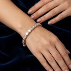 Rose gold bracelet on a wrist with a dark blue velvet background