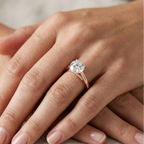 Close-up of a hand wearing a diamond ring on a neutral background