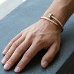 Hand wearing a gold bracelet on a gray surface