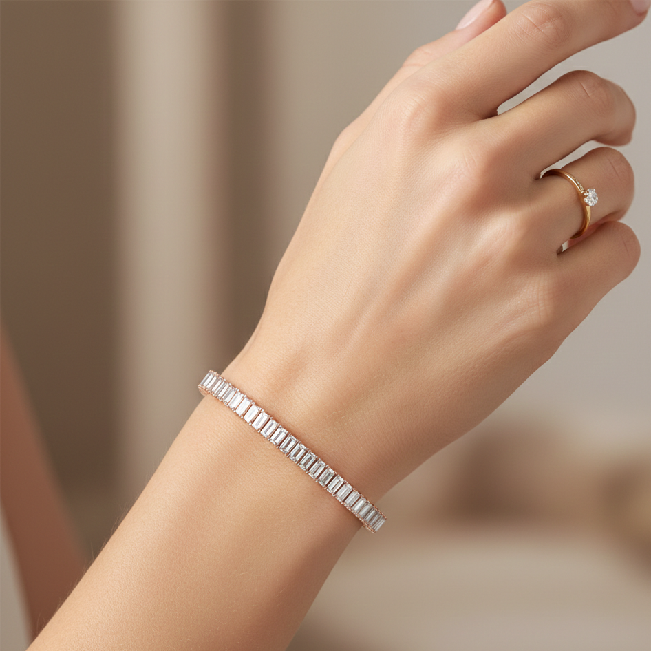 Hand wearing a silver bracelet and gold ring on a blurred background