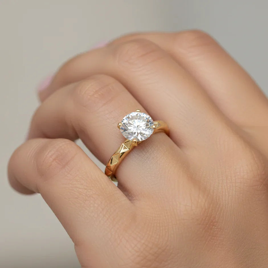 Gold ring with a diamond on a hand against a neutral background