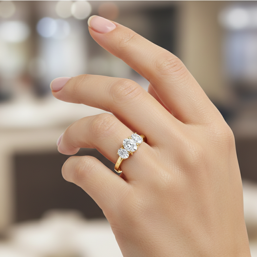 Hand wearing a gold ring with three diamonds on a blurred background