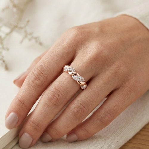 Hand wearing a rose gold ring with diamonds on a light background